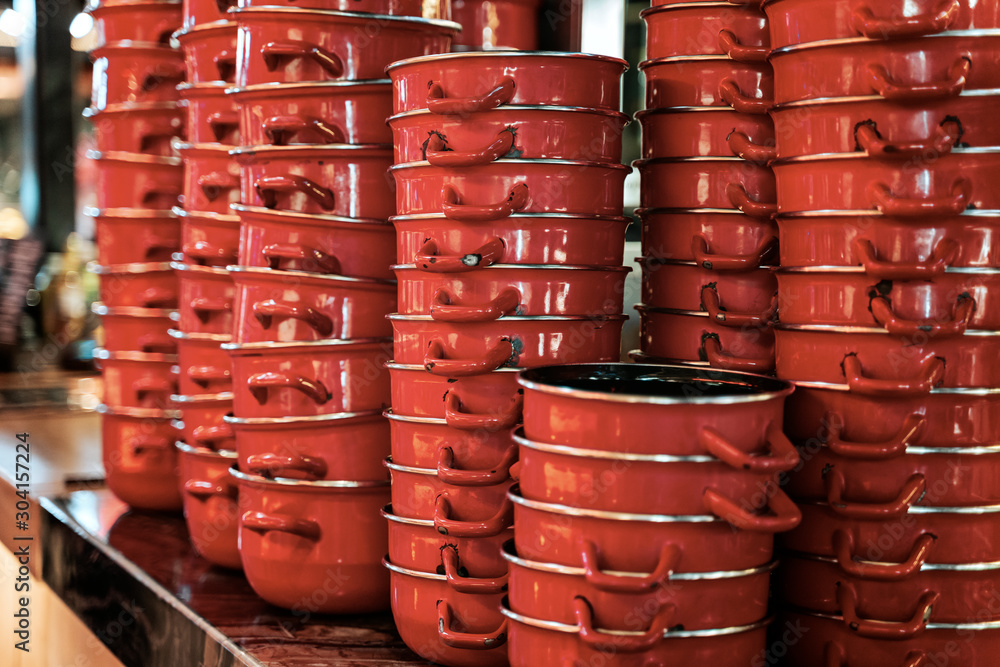 Stack of assorted red ceramic and steel cooking pans Stack of assorted red ceramic and steel cooking pans
