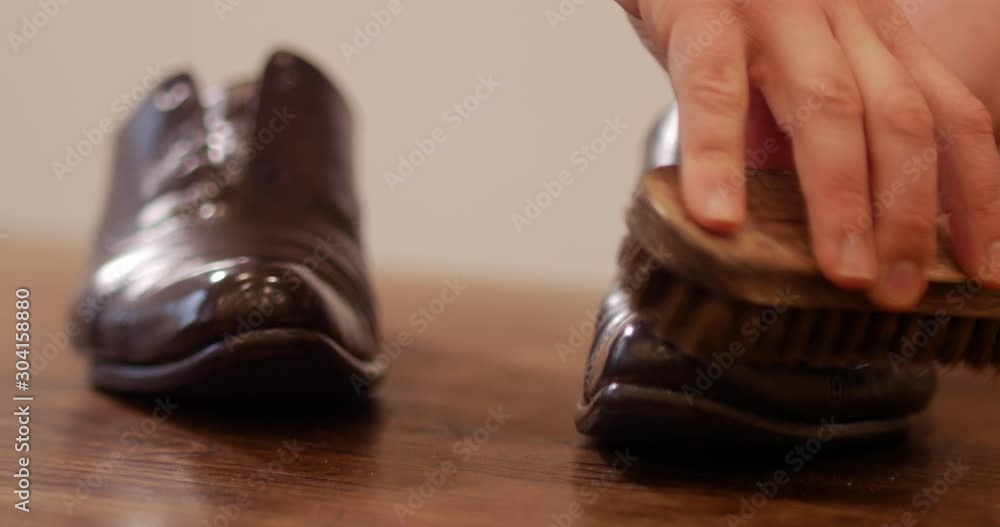 close shot of handsome shoemaker buffing leather brogue shoes with shoe cream. close shot of handsome shoemaker buffing leather brogue shoes with shoe cream.