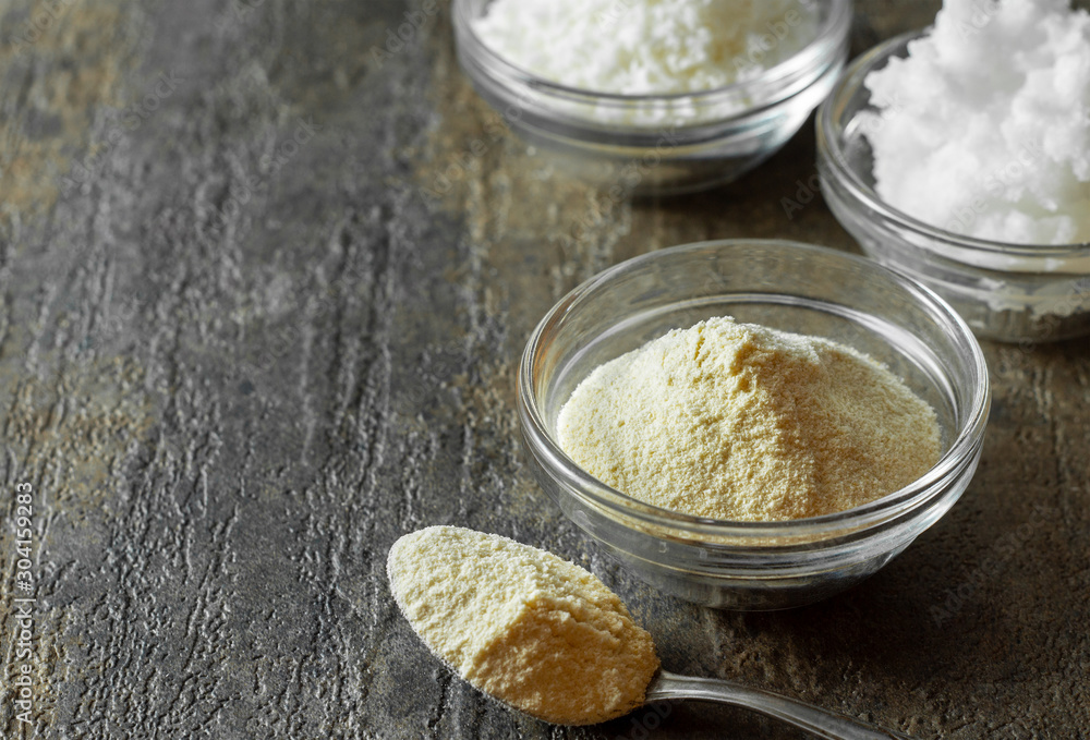 organic coconut flour in glass bowl along with a spoonful of coconut flour. organic coconut flour in glass bowl along with a spoonful of coconut flour.