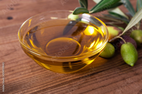 bowl of olive oil and olives with olive branches