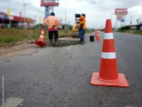 The road is under construction and has a red rubber cone on the road.