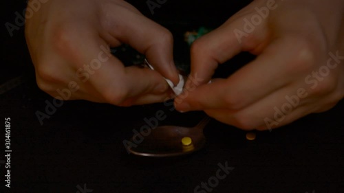 Male jands Make a drug from yellow pills in a spoon on a black background hd stock footage photo