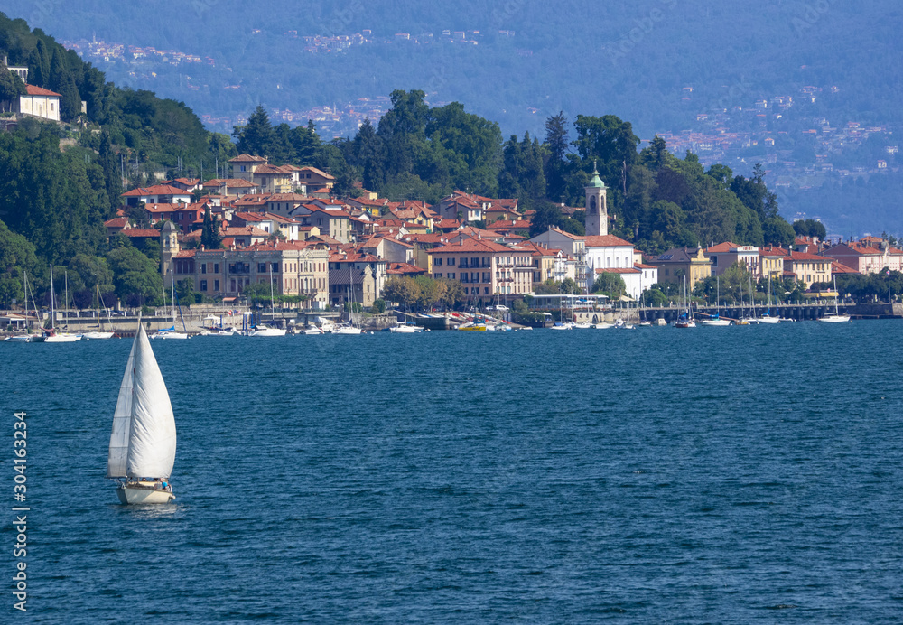 water sports on Lake Maggiore, a sailboat leaves the marina of Meina.Italy