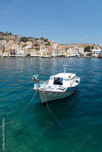 Boat at the harbor of Simi Dodecanese Greece. White boat in port island Symi with colorful buildings and blue sea