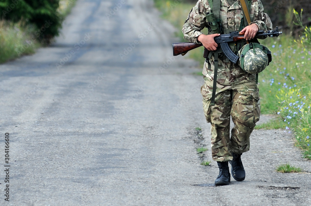 A soldier with weapon are patrols the road. Armed forces, troops, army. East of Ukraine. A soldier with weapon are patrols the road. Armed forces, troops, army. East of Ukraine.