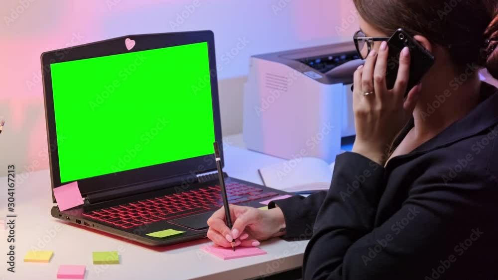 Business Woman Using Laptop Computer Pinter And Phone In Home Office. Chroma key green screen on monitor. White, pink and purple color isolated on background. Business Woman Using Laptop Computer Pinter And Phone In Home Office. Chroma key green screen on monitor. White, pink and purple color isolated on background.