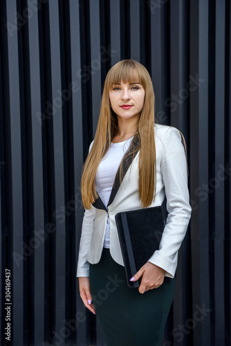Beautiful lady in business suit holding tablet and posing on abstract background