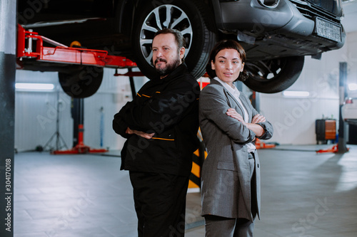 A worker and a lady in happy costume pose in front of the camera in a car service