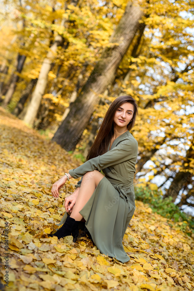 Female portrait. Brunette woman portrait in autumn park wearing olive dress Female portrait. Brunette woman portrait in autumn park wearing olive dress