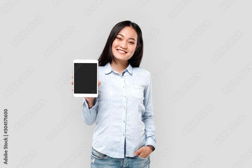 Freestyle. Asian girl student isolated on white showing screen of digital tablet copy space smiling cheerful