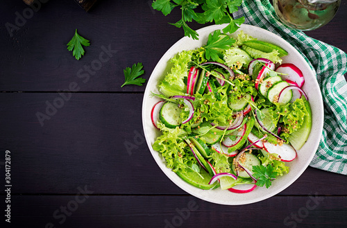 Healthy vegan food. Vegetarian vegetable salad of radish  cucumbers  lettuce  and red onion.  Top view  copy space