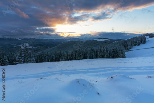 A bright winter in the Ukrainian Carpathian Mountains with snow-capped mountain peaks and picturesque meadows with mountain lodges and hikers. © reme80