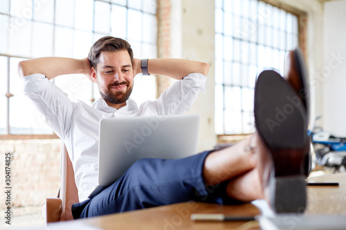 Young businessman with legs on the desk