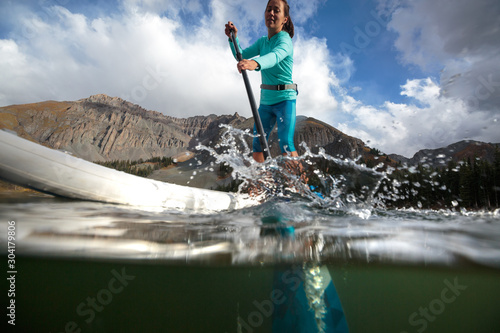 A woman paddle boards on an inflatable SUP at Alta Lakes near Telluride, Colorado in autumn in the San Juan Mountains. photo