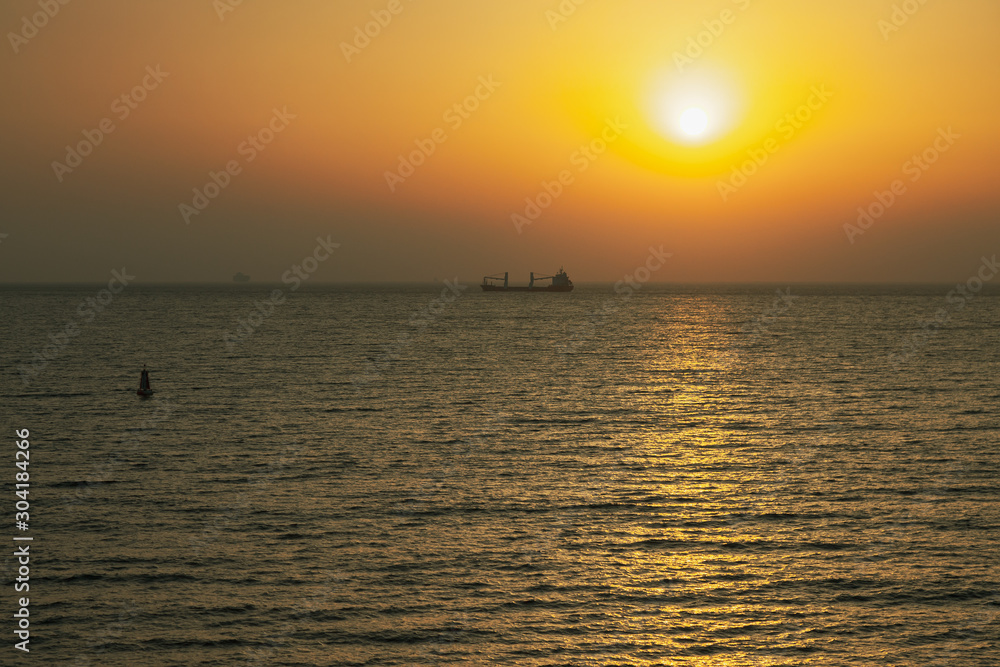 Colorful sunset in the Mediterranean sea with a cargo ship in a distance. View from the deck of a cruise ship