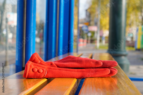 Fotografie red women's gloves forgotten on a bench or at a bus stop on a warm Sunny day