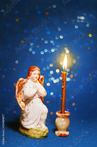 porcelain angel with candle on green bokeh background