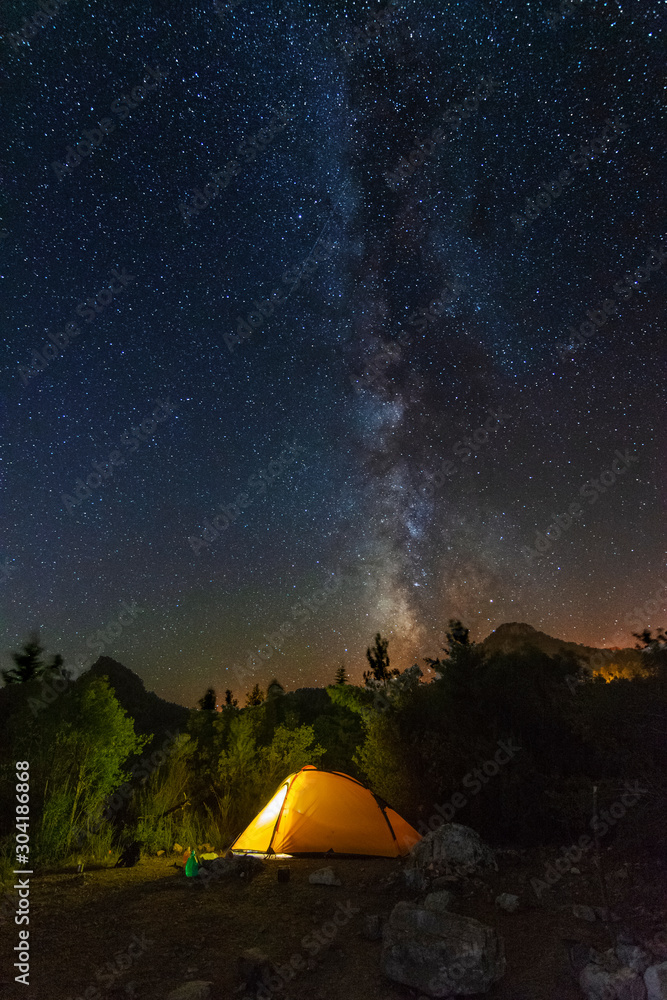 starry night with the Milky Way on the Turkish Mediterranean coast amidst the rocky mountains with tourists in a yellow tent