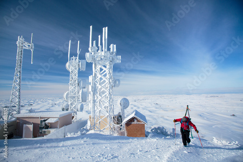 Skier walking by ice covered weather station photo