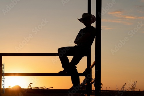 silhouette of cowboy on fence