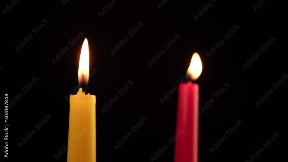 two candles are burning red and yellow one of which is calm, and the other is swaying two candles are burning red and yellow one of which is calm, and the other is swaying