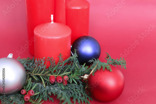 spruce branches with Christmas balls of different colors and  4 red Christmas candles on a red background in the corner place for text. concept new year and Christmas