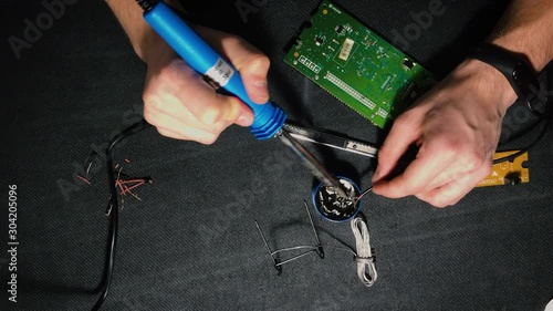 Young engineer soldering a board. View from above