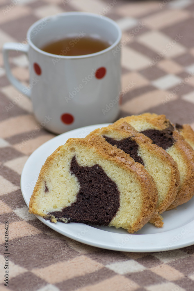 Gugelhupf on white plate on picnic blanket, very tasty edible two-colored Czech sweet cake called babovka, sliced ready to eat Gugelhupf on white plate on picnic blanket, very tasty edible two-colored Czech sweet cake called babovka, sliced ready to eat