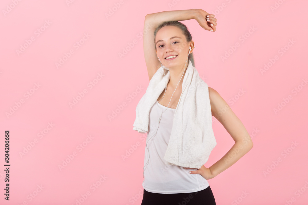 beautiful young slim woman in sportswear on a pink background listens to music beautiful young slim woman in sportswear on a pink background listens to music