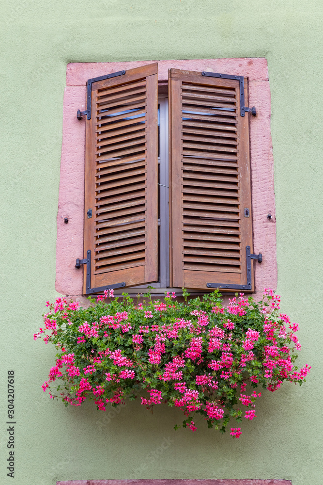Window with closed wooden shutters on ancient wall