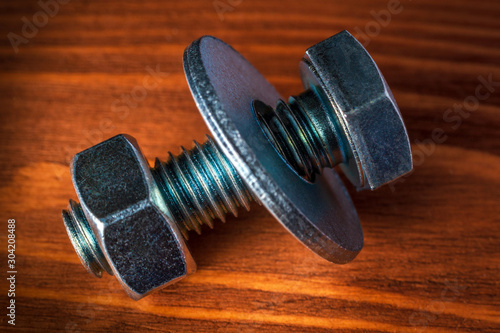 Metal bolt and nut on wooden background are used in construction photo