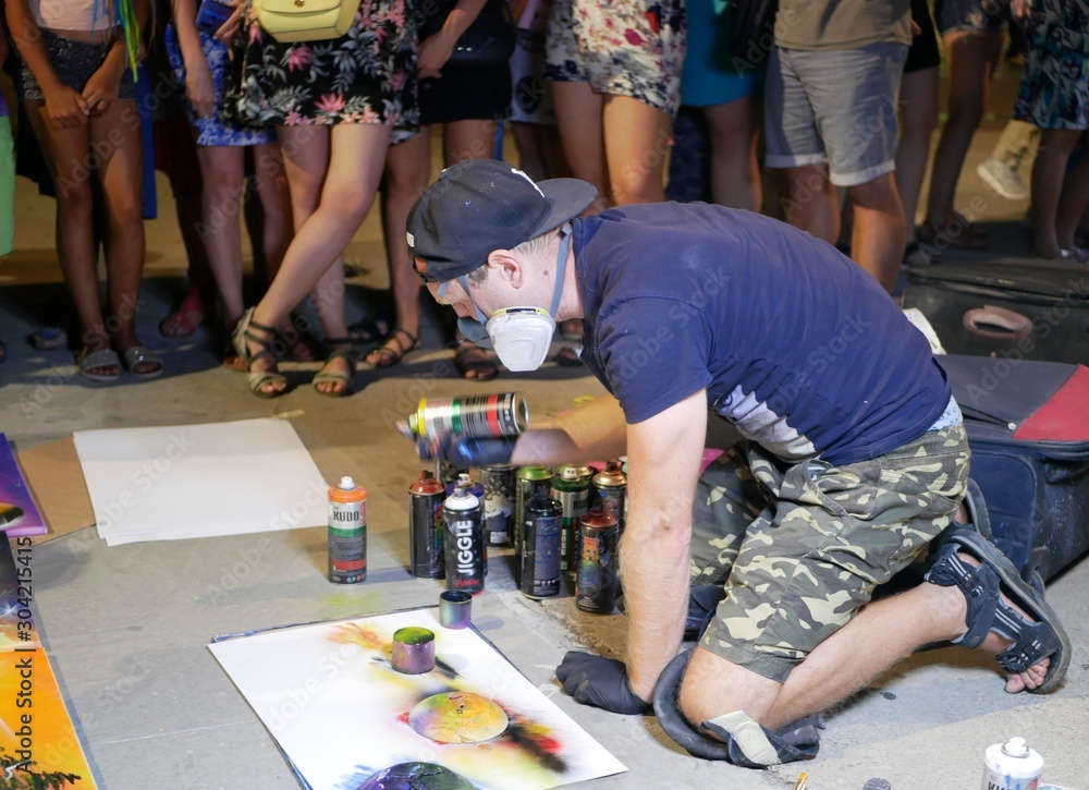 A young artist paints a picture of multicolored spray paint at night in