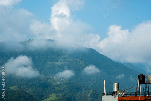 Strong white clouds over a mountain covered by forest. Phewa Lake in Pokhara  Nepal  in the morning