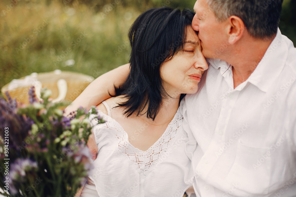 Adult couple in a summer field. Handsome senior in a white shirt. Woman in a white blouse Adult couple in a summer field. Handsome senior in a white shirt. Woman in a white blouse