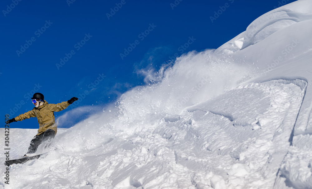 Freerider snowboarder moving down the slope in the mountains at high speed in snow powder