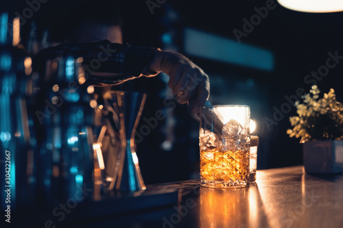 Canvas Print barman preparing cocktail on blue background in club