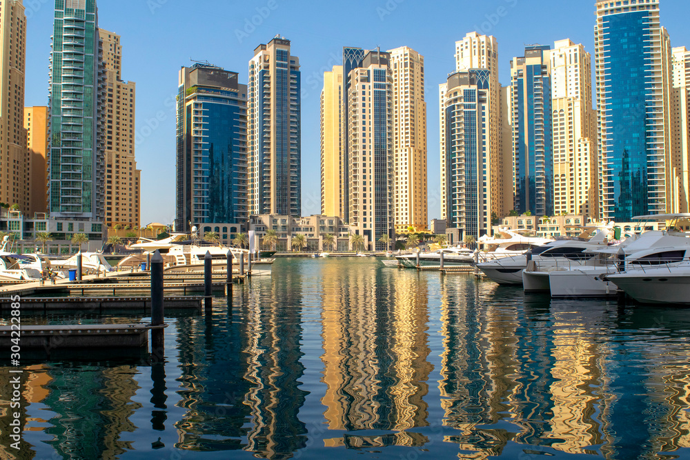 Fototapeta premium Dubai Marina district with beautiful buildings and yachts. Dubai Marina pier.