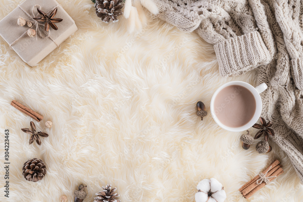 Autumn or winter composition. Gift box Coffee cup, cinnamon sticks, anise stars, beige sweater with knitted blanket on cream color gray fluffy background. Flat lay top view copy space. - obrazy, fototapety, plakaty 