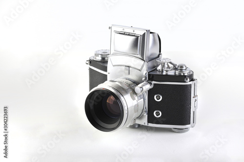 The old German 35 mm SLR film camera with lens 58 mm lens on a white cement background. photo