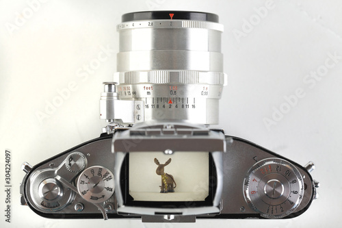 Tableau sur toile The old German 35 mm SLR film camera with lens 58 mm lens on a white cement background