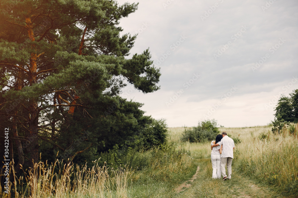 Adult couple in a summer field. Handsome senior in a white shirt. Woman in a white blouse Adult couple in a summer field. Handsome senior in a white shirt. Woman in a white blouse