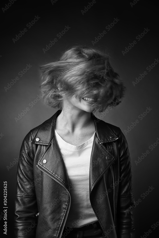 Black and white portrait of happy teenage girl on dark background