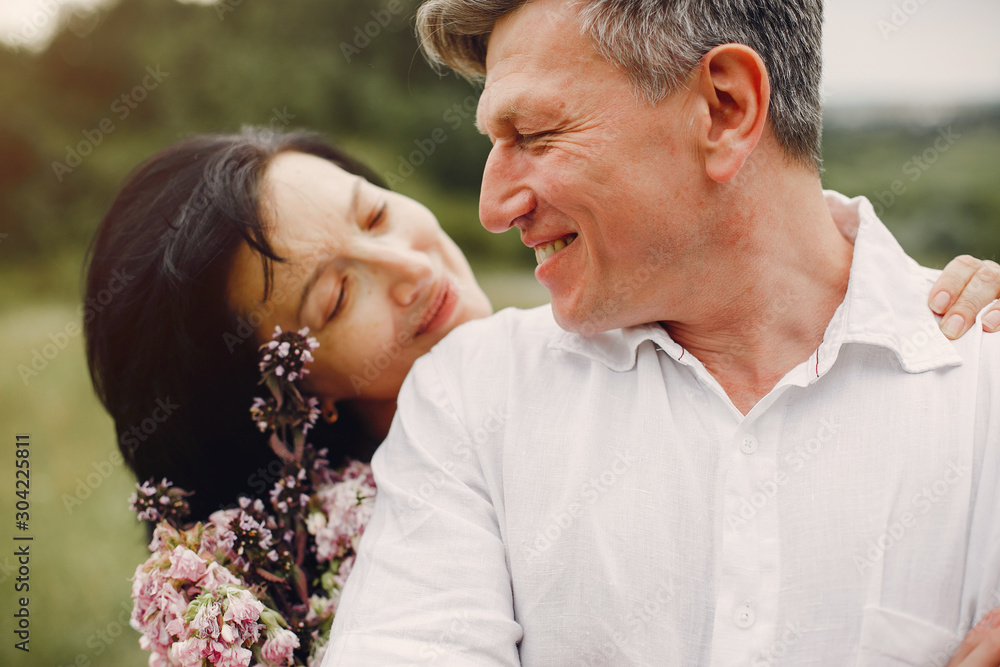 Adult couple in a summer field. Handsome senior in a white shirt. Woman in a white blouse Adult couple in a summer field. Handsome senior in a white shirt. Woman in a white blouse