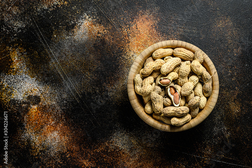 Raw unshelled peanuts in the shell. Organic groundnut. Black background. The view from the top. Space for text