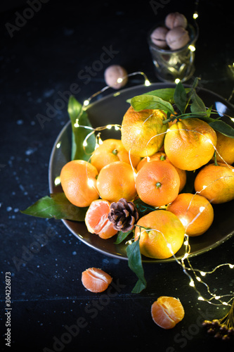 Tangerines or clementines in grey plate with bokeh lights in Christmas or New year arrangement  copy space