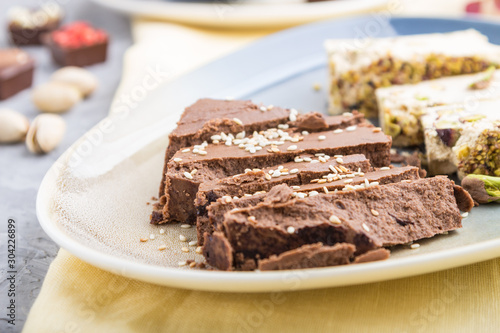 traditional arabic sweets sesame halva with chocolate and pistachio and a cup of coffee on a gray concrete background. side view, selective focus.