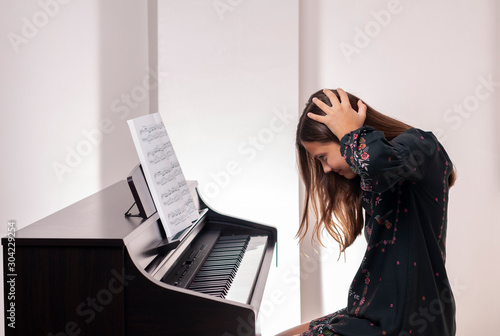 Girl learning piano, she is sad, photo