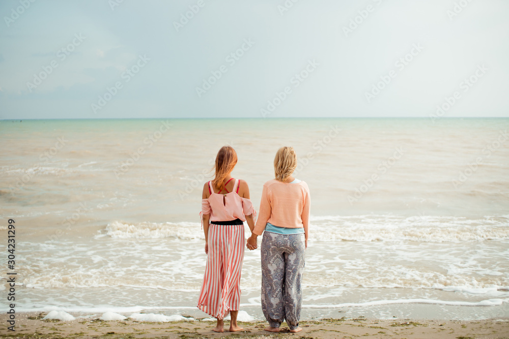 Mother and adult daughter hold hands outdoors