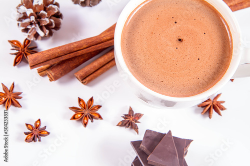 Cup of hot chocolate with cinnamon, anise stars, pieces of dark chocolate and some cones