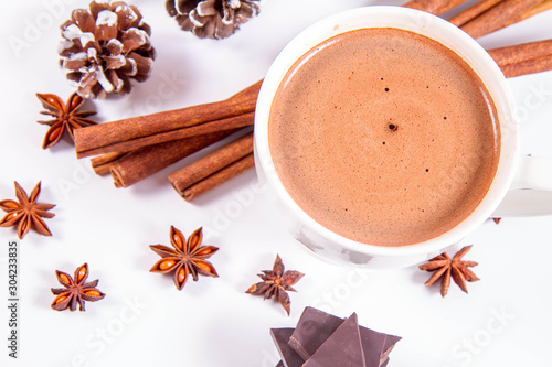 Cup of hot chocolate with cinnamon,  anise stars, pieces of dark chocolate and some cones